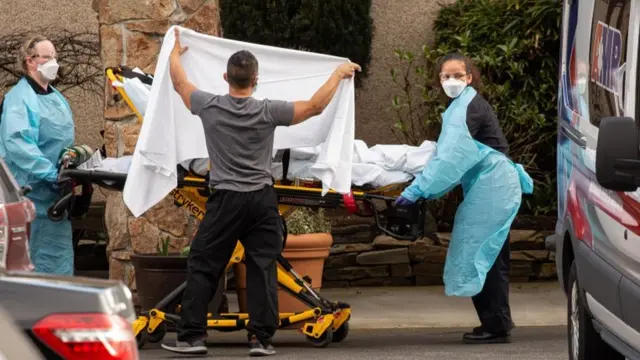 Healthcare workers transport a patient on a stretcher into an ambulance at Life Care Center of Kirkland in Kirkland, Washington