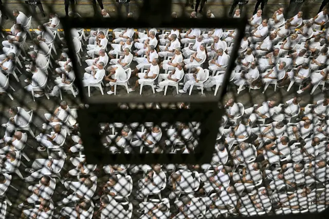 Presos en el Cecot, El Salvador, sentados en filas detrás de rejas durante una audiencia judicial remota en abril de 2026.