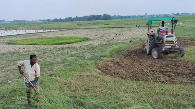 पानी नपरेकाका कारण सुक्खा बनेको खेतमा खनजोत गर्दै किसानहरू