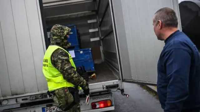 ਪੁਲਿਸ ਕਰਮਚਾਰੀ, ਇੱਕ ਟਰੱਕ ਦੀ ਜਾਂਚ ਕਰਦੇ ਹੋਏ