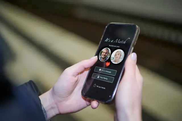 Mãos seguram um celular com a notificação de 'match' de um aplicativo de namoro.