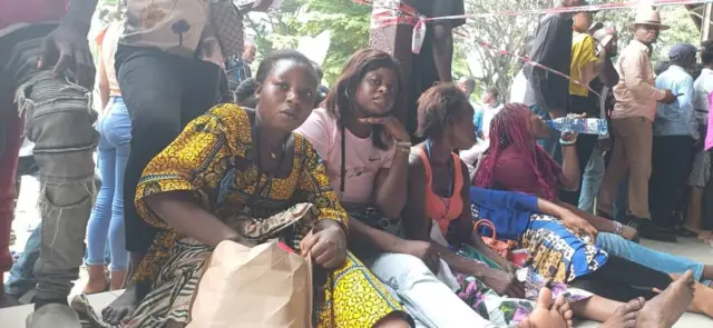 Des femmes assises à même le sol, attendent