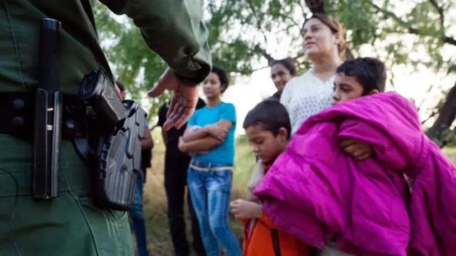 Oficial estadounidense interroga a migrantes en Texas.