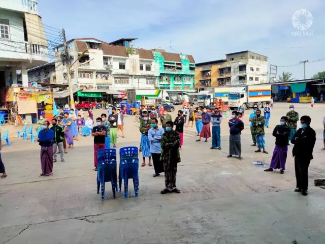 เจ้าหน้าที่มูลนิธิรักษ์ไทย องค์กรพัฒนาเอกชนที่ทำงานด้านสุขภาพของแรงงานข้ามชาติ ช่วยสนับสนุนการเป็นล่ามแปลภาษาให้กับพยาบาลภาคสนาม และจัดคิวเข้ารับการตรวจอย่างเว้นระยะห่าง