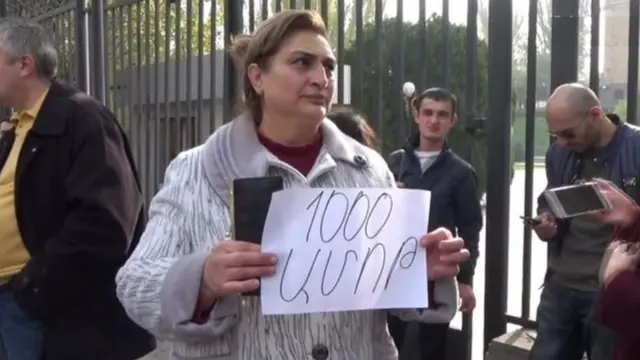 Parlamentin qarşısında keçirilən etiraz aksiyasında qadın "1000 dram (vermək) ayıbdır" şüarını tutur