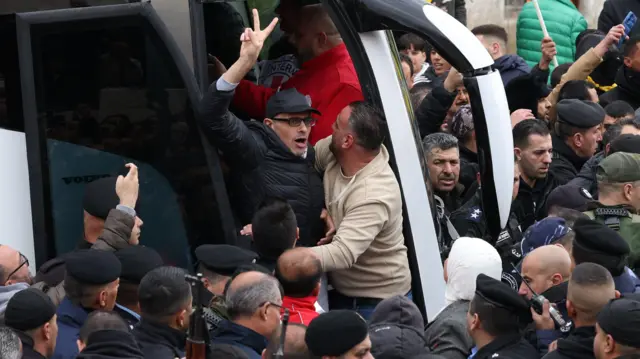 Un prisionero palestino liberado sale de un autobús rodeado de una muchedumbre.