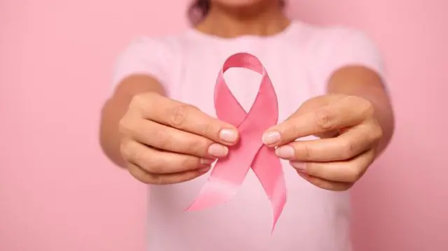 Mulher segurando fita da campanha Outubro Rosa