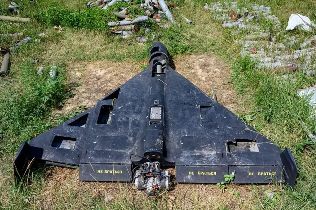 Un dron de color negro con escritura en ruso en las alas, yace derribado sobre césped.