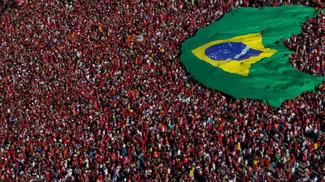 Multidão vestidaaplicativos de apostas de futebolvermelhoaplicativos de apostas de futebolposseaplicativos de apostas de futebolLula carregando bandeira do Brasil