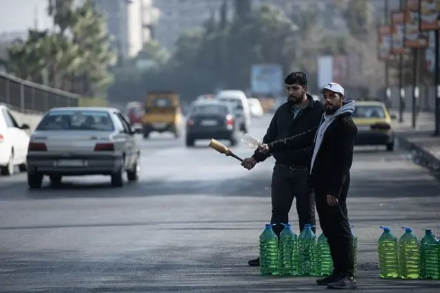 Suriye'nin Şam kentinde yakıt üretimi talebi karşılayamadığı için yol kenarında satıcılar sürücülere benzin ve dizel satıyor, 26 Aralık 2024.