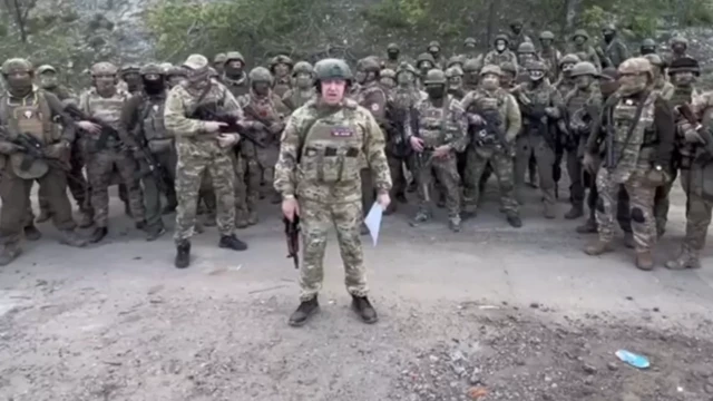 Homem com roupa militar em frente a outros militares