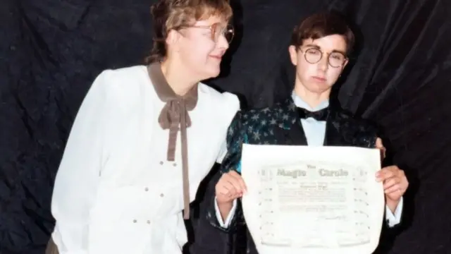 Sophie disfrazada como Raymond recibiendo el diploma