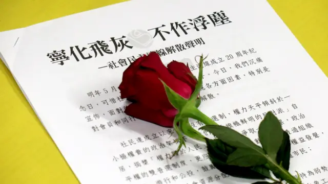 香港社民连解散记者会上展示的一份书面声明与一朵红玫瑰（BBC中文图片29/6/2025）