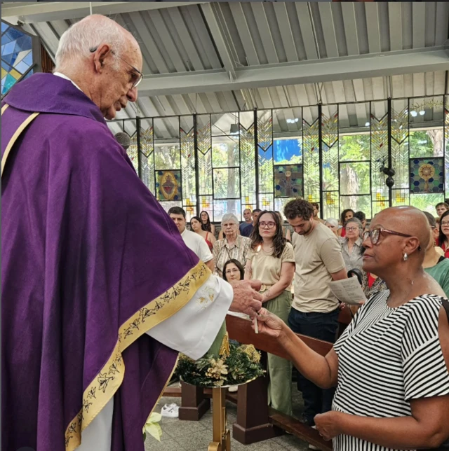 Padre Julio celebrando missa e interagindo com uma fiel