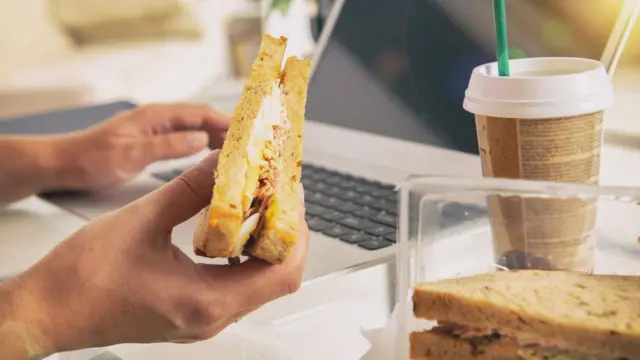 Mão segurando sanduíche e, ao lado, copoganhar dinheiro com cassinocafé