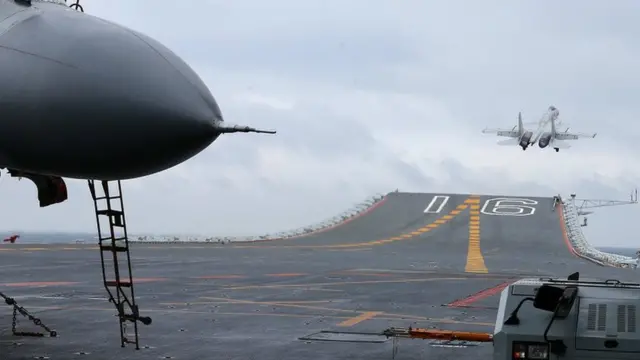 中國海軍發佈刊登的中國航母編隊殲-15艦載戰鬥機起降的兩張照片之一(殲-15戰機在遼寧號上起飛)。