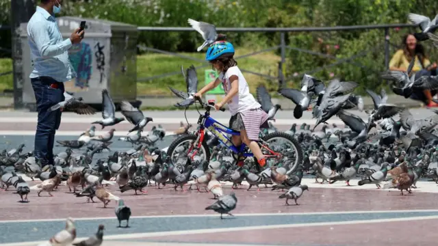 فتاة تلعب مع الحمام في ساحة كاتالونيا، إسبانيا، في 18 مايو/أيار 2020