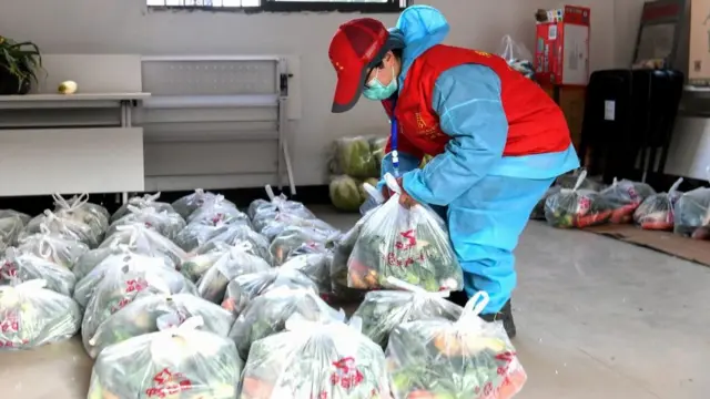 Một người đưa hàng chuẩn bị rau quả tươi để giao cho người dân Vũ Hán