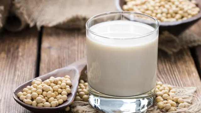 Vaso con bebida de soja y semillas de soja en una cuchara.