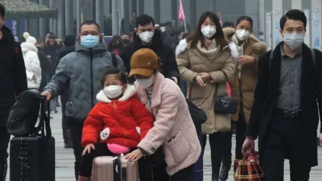 Viajeros chinos caminando con mascarilla.