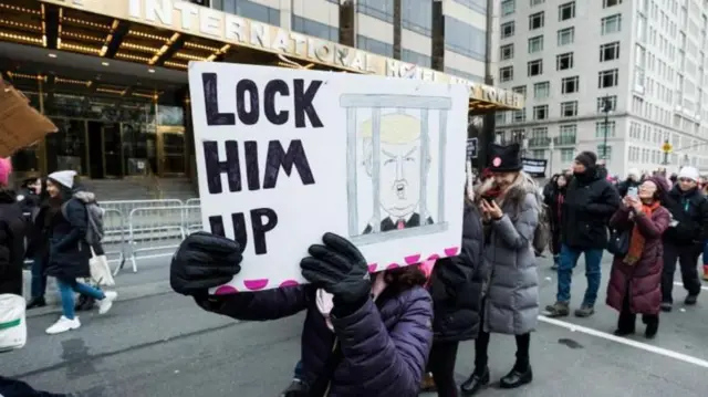 మన్హటన్లో ట్రంప్ టవర్ వద్ద ట్రంప్ను జైల్లో పెట్టండి అనే ప్లకార్డుతో మహిళ