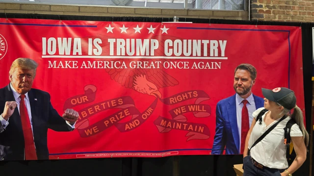 Una mujer mira un cartel con Trump y Vance que dice Iowa es el país de Trump, Haz a Estados Unidos Grande Otra Vez.