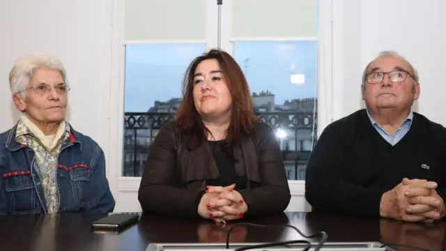 Francesca Satta no meio de uma senhora e de um senhor, os três sentados à mesa. 