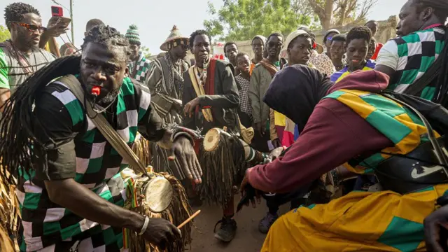 Para pengikut Baye Fall, beberapa di antaranya mengenakan pakaian tambal sulam warna-warni, menabuh drum dan bersiul di sebuah jalan di Diourbel, Senegal