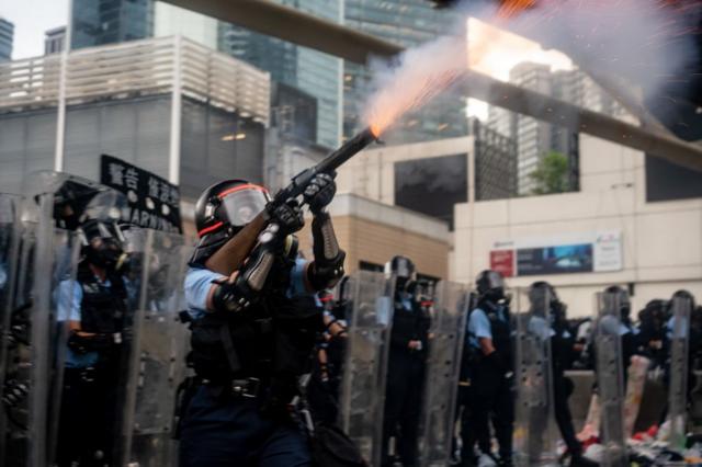 6月12日，一名香港警察正向示威者施放催泪瓦斯。