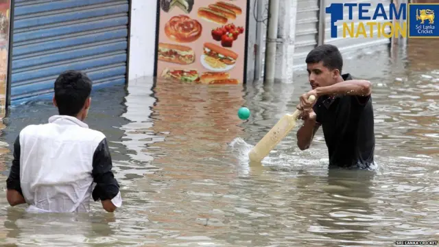 ගංවතුරේ ක්‍රිකට් ක්‍රීඩා කරන තරුණයන් දෙදෙනක්