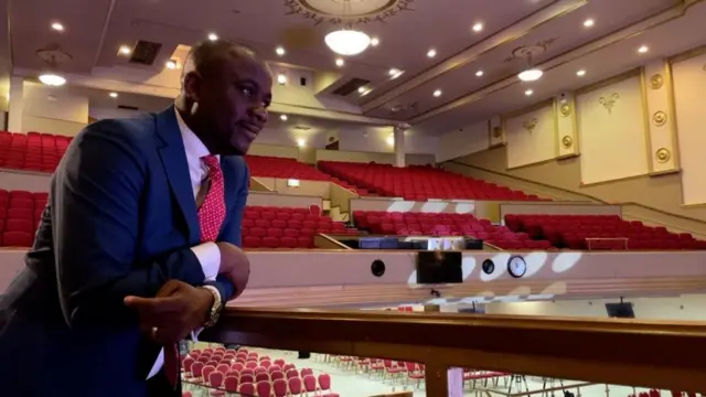 አዲጎኬ ድርጅቱ እድሳት ያደረገለት አዳራሽ ውስጥ ቆሞ 