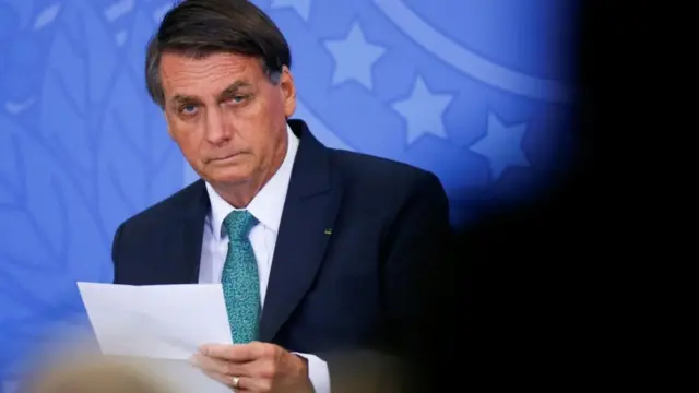 Bolsonaro sentado em evento com feição séria olhando para frente