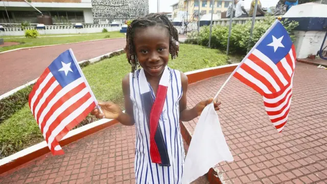 Umwana w'umukobwa yifotoje afashe ibendera ry'igihugu ku munsi wahariwe ibendera ry'igihugu i Monronvia, muri Liberia, 24/08/2021