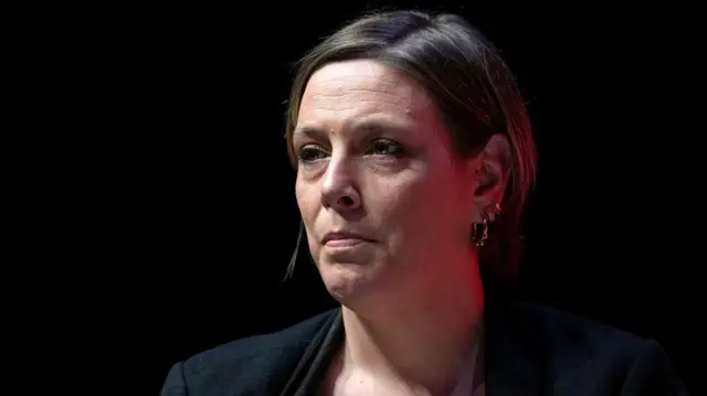 Jess Phillips MP. pictured against black background, looks off to the side 