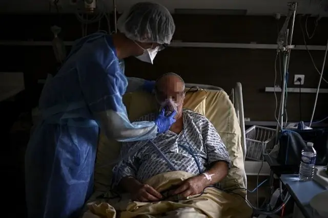 একজন পুরুষ রোগীকে ভেন্টিলেশন দিচ্ছেন হাসপাতালের একজন কর্মী  