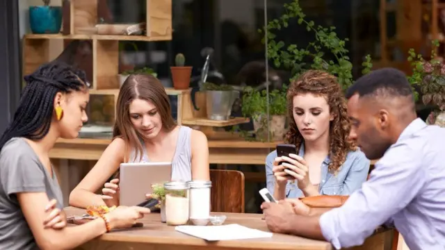 شباب يجلسون في أحد المقاهي ويحدقون في هواتفهم