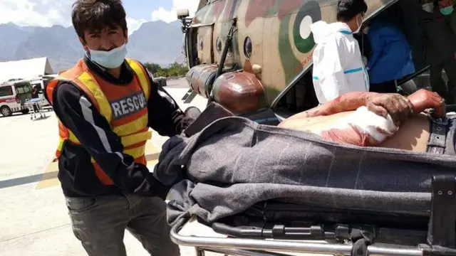 巴基斯坦吉尔吉特一名救援人员把客车爆炸事故生还伤者从直升机卸下（新华社图片14/7/2021）