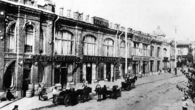 Старе чорно-біле фото вулиці міста з крамницями і кінними візками