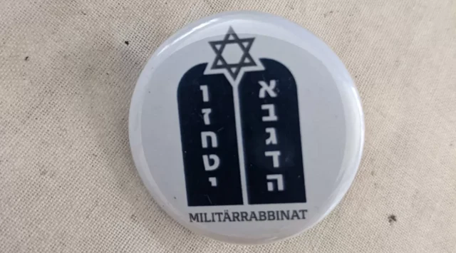 Um distintivo de capelania militar judaica moderna, com escrita em hebraico e alemão e a estrela de David no topo