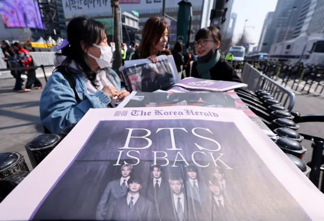 BTS 컴백 공연일인 21일 오전 서울 광화문광장 인근에서 외국인 관광객들이 주요 일간지 BTS 관련 호외를 수집하고 있다