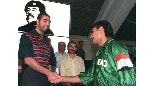 फुटबॉल सामन्यानंतर इराकी संघातल्या एका खेळाडूला भेटताना उदय सद्दाम हुसैन