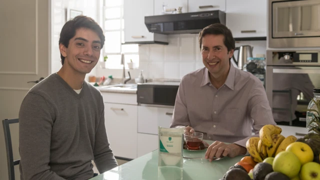 Javier e o pai sorriem, sentados à mesa da cozinharoleta brasileira da evolutioncasa