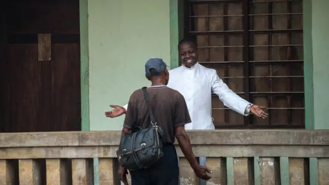 Le père Lucien Ambunga, un prêtre qui a survécu au virus Ebola, accueille un fidèle à l'église Saint Joseph d'Itipo, en RDC.