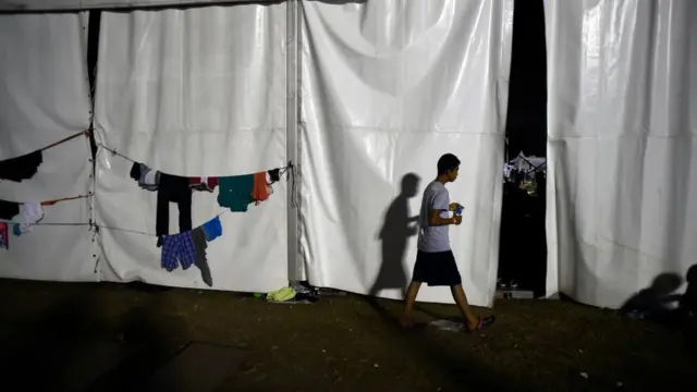 Joven de la caravana de migrantes caminando cerca a unas prendas colgadas.