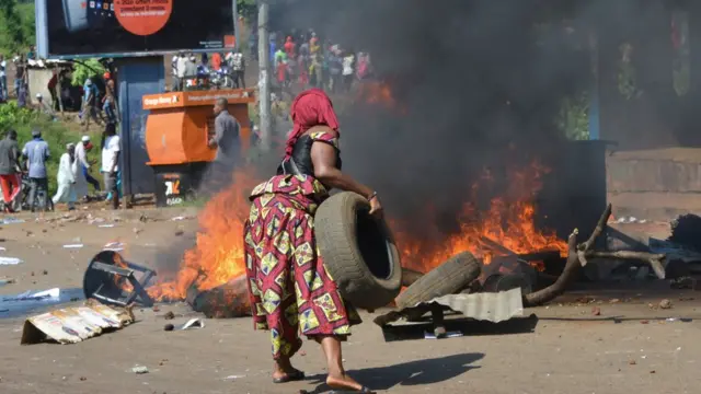 Un manifestant brûle des pneus pendant les funérailles après les dernières manifestations de rue et les troubles qui ont fait neuf morts à Conakry, le 4 novembre 2019. - Des foules de manifestants ont défilé dans la capitale guinéenne de Conakry le 24 octobre 2019 lors de la dernière série de manifestations contre le président Alpha Conde, accusé de vouloir contourner la constitution pour un troisième mandat en fonction.