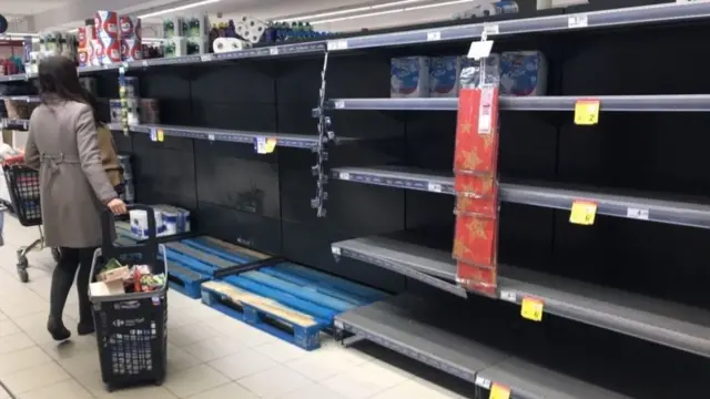 Mujer frente a unos estantes vacíos en un supermercado