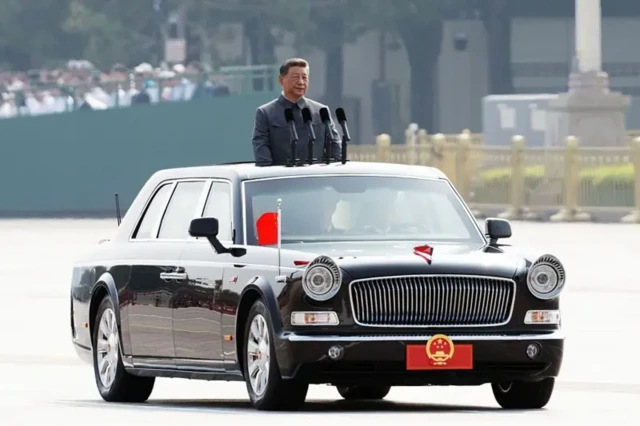 Сі Цзіньпін на параді стоїть у відкритому чорному автомобілі з китайським прапорцем