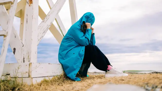 فتاة تجلس وحدها منعزلة عن العالم حولها في منطقة قاحلة.