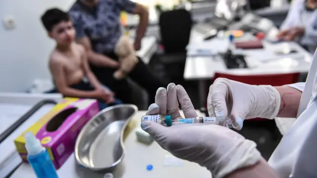 Lekarz przygotowuje się do podania szczepionki przeciw odrze dziecku w klinice w Bukareszcie w Rumunii.