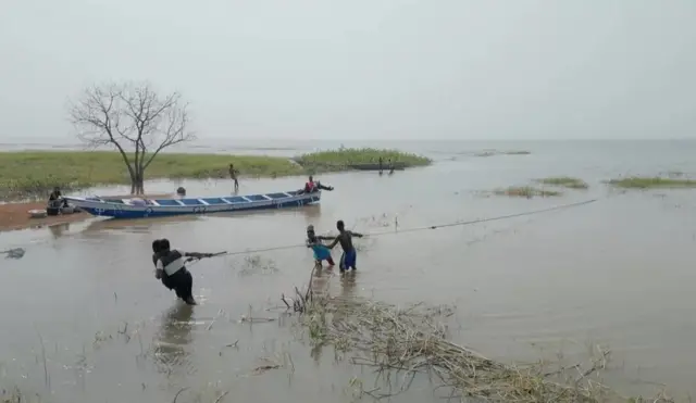 أناسٌ يسحبون قارباً إلى الشاطئ